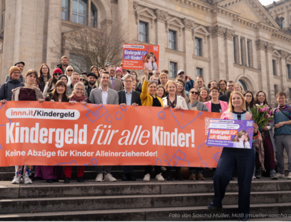 Mães solo e apoiadores segurando faixa Kindergeld für alle Kinder em frente ao Bundestag, Berlim