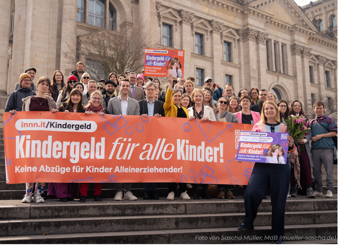 Mães solo e apoiadores segurando faixa Kindergeld für alle Kinder em frente ao Bundestag, Berlim
